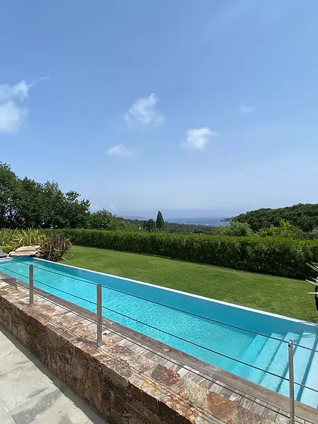 Piscine extérieure avec revêtement en Chukum et eau turquoise, entourée d'un jardin.