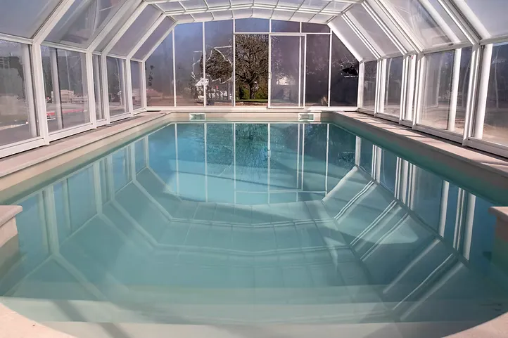 Piscine intérieure avec revêtement en Chukum sous une toiture vitrée.